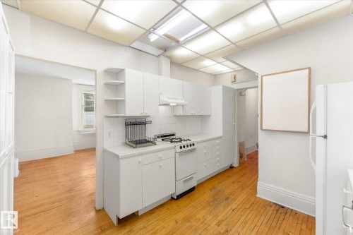 Kitchen featuring white cabinetry, a gas range, white tile backsplash, and wood-finish flooring - 10921 126 Street, Edmonton, AB - Indoor Photo Showing Kitchen