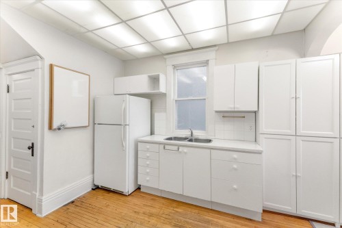 Kitchen area featuring white cabinetry, a double basin stainless steel sink, and white countertops - 10921 126 Street, Edmonton, AB - Indoor Photo Showing Other Room