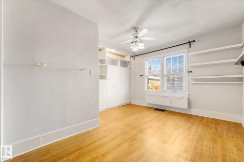Hardwood flooring complements a room featuring built-in shelving, white cabinetry, and a ceiling fan with integrated lighting - 10921 126 Street, Edmonton, AB - Indoor Photo Showing Other Room
