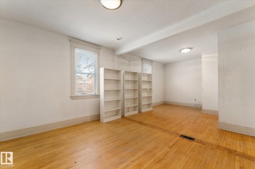 Bright room featuring wood-finish flooring, two windows with trim, and three built-in shelving units - 10921 126 Street, Edmonton, AB - Indoor Photo Showing Other Room
