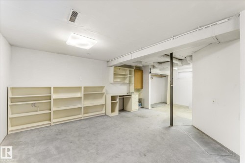 Spacious lower-level room featuring wall-to-wall carpeting and built-in shelving units - 10921 126 Street, Edmonton, AB - Indoor