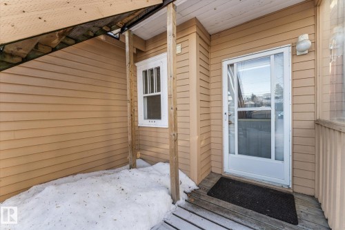 Front entrance featuring a storm door, wood-finish siding, white trim window, and a wood porch deck - 10921 126 Street, Edmonton, AB - Outdoor With Exterior