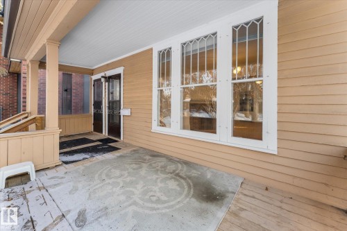 Covered porch entry featuring a wood-panel ceiling, light tan siding, and a concrete patio with an embossed design - 10921 126 Street, Edmonton, AB - Outdoor With Exterior