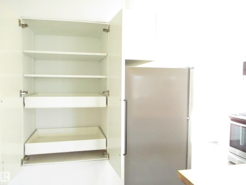 White kitchen cabinetry featuring interior shelving and two pull-out drawers - 12115 64 Street Nw, Edmonton, AB - Indoor With Storage