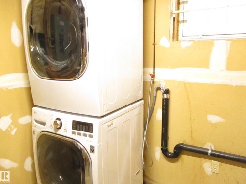 Laundry area featuring a stacked washer and dryer - 12115 64 Street Nw, Edmonton, AB - Indoor Photo Showing Laundry Room