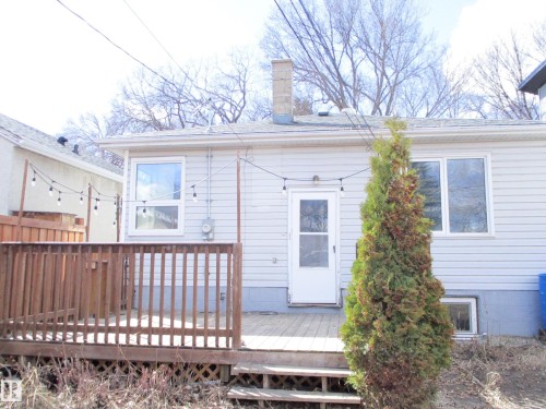 Rear exterior of the property featuring a wooden deck with railing, - 12115 64 Street Nw, Edmonton, AB - Outdoor