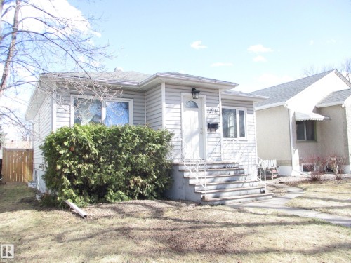 Single-story residence featuring light-colored siding, a covered front entry, and concrete steps with metal railings - 12115 64 Street Nw, Edmonton, AB - Outdoor