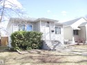 Single-story residence featuring light-colored siding, a covered front entry, and concrete steps with metal railings - 12115 64 Street Nw, Edmonton, AB  - Outdoor 