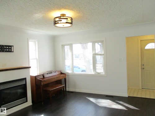 Spacious interior featuring dark wood-finish flooring, a built-in fireplace, - 12115 64 Street Nw, Edmonton, AB - Indoor With Fireplace