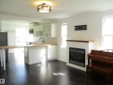 Modern kitchen and living area featuring dark wood-finish flooring - 12115 64 Street Nw, Edmonton, AB  - Indoor Photo Showing Other Room With Fireplace 