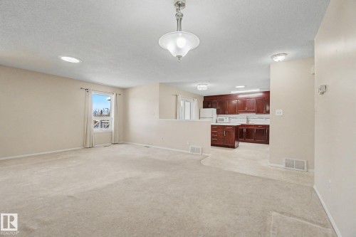 Spacious living area featuring neutral carpeting, a large window, and recessed lighting - 1542 54 Street, Edmonton, AB - Indoor Photo Showing Other Room