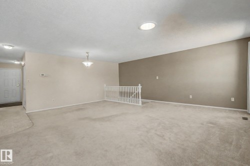 Spacious living area featuring neutral carpeting and a white railing - 1542 54 Street, Edmonton, AB - Indoor