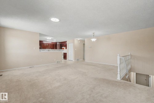 Spacious carpeted living area with recessed lighting and a classic chandelier - 1542 54 Street, Edmonton, AB - Indoor