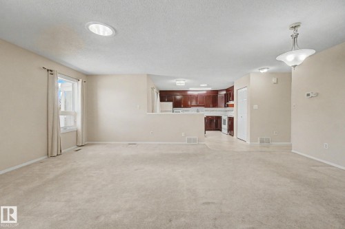 Carpeted living area with a large window, a circular recessed light fixture, and a decorative pendant light - 1542 54 Street, Edmonton, AB - Indoor Photo Showing Other Room