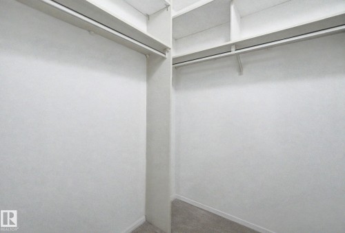 Spacious walk-in closet featuring white painted walls and shelving, multiple clothing rods, and gray carpet flooring - 1542 54 Street, Edmonton, AB - Indoor