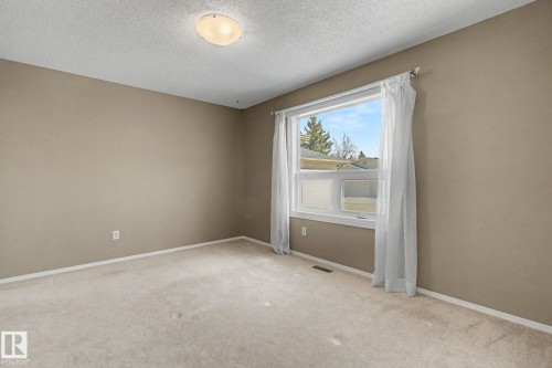 Neutral-toned room featuring a large window, light-colored carpeting, and a flush mount ceiling light fixture - 1542 54 Street, Edmonton, AB - Indoor Photo Showing Other Room
