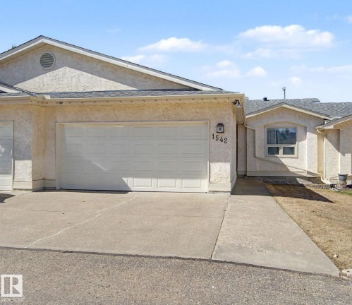 Stucco exterior featuring multiple garage doors, a concrete driveway, and a shingled roof - 1542 54 Street, Edmonton, AB - Outdoor