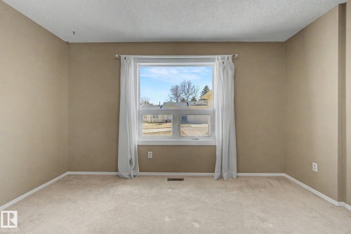 Bright interior space featuring a double-hung window, light-colored carpeting, and neutral-toned walls - 1542 54 Street, Edmonton, AB - Indoor Photo Showing Other Room