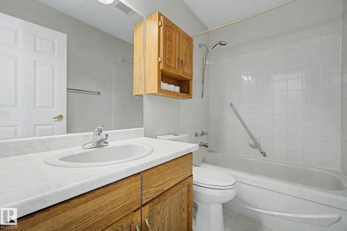 Bathroom featuring a wood-finish vanity with an integrated sink and laminate countertop - 1542 54 Street, Edmonton, AB - Indoor Photo Showing Bathroom