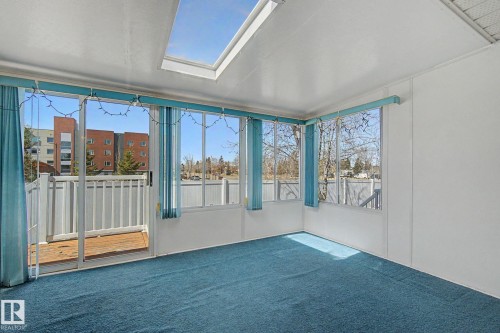 Sunroom featuring a skylight, multiple windows, blue carpeting, and white walls - 1542 54 Street, Edmonton, AB - Indoor Photo Showing Other Room