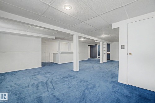 Expansive room featuring blue carpeting, white walls, and a grid-patterned ceiling with recessed lighting - 1542 54 Street, Edmonton, AB - Indoor Photo Showing Other Room