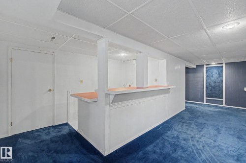 Lower level space featuring a built-in bar with a light-toned countertop, blue carpeting, and a dropped ceiling - 1542 54 Street, Edmonton, AB - Indoor Photo Showing Other Room