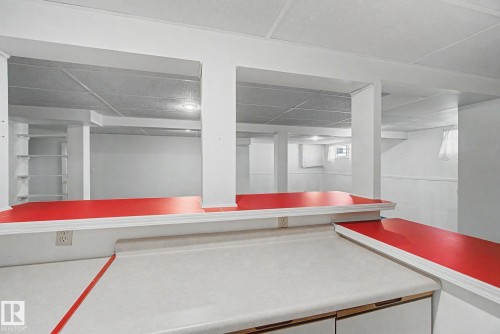 Lower level space featuring a built-in counter area with laminate countertops and a red accent bar top - 1542 54 Street, Edmonton, AB - Indoor