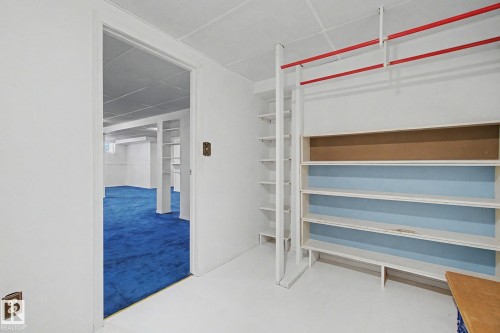 Built-in shelving with red-painted hanging rods, providing extensive storage options - 1542 54 Street, Edmonton, AB - Indoor Photo Showing Other Room