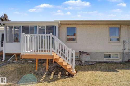Raised wood deck with white railing, leading to an enclosed sunroom featuring multiple windows - 1542 54 Street, Edmonton, AB - Outdoor