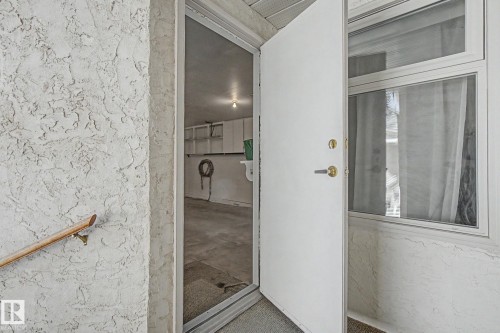 Textured stucco exterior wall with a wood handrail - 1542 54 Street, Edmonton, AB -  Photo Showing Bathroom
