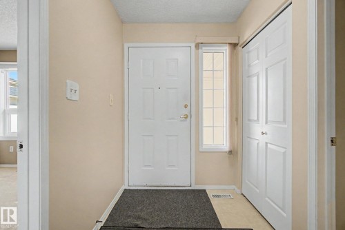 Entryway featuring a white paneled door, a side window with grilles, and a bi-fold closet with white paneled doors - 1542 54 Street, Edmonton, AB - Indoor Photo Showing Other Room