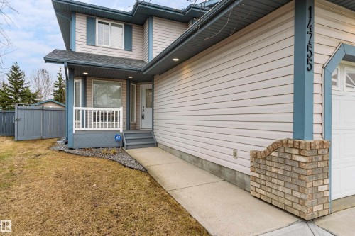 Siding exterior featuring a partial brick facade, attached garage, and covered front porch with white railing - 14755 131 Street Nw, Edmonton, AB - Outdoor With Deck Patio Veranda With Exterior