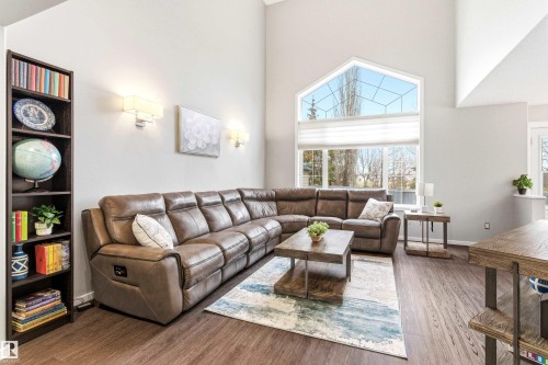 Open-concept living area featuring vaulted ceilings, wood-finish flooring, and a large picture window with an arched transom - 14755 131 Street Nw, Edmonton, AB - Indoor Photo Showing Living Room