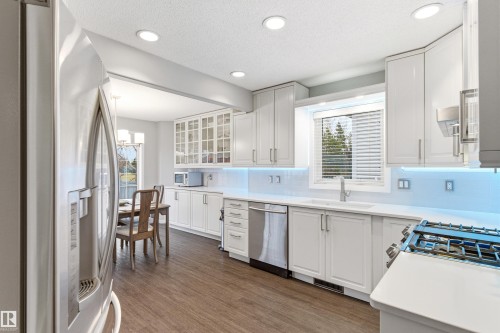 Kitchen featuring white cabinetry, wood-finish flooring, recessed lighting, and a subway tile backsplash with under-cabinet lighting - 14755 131 Street Nw, Edmonton, AB - Indoor Photo Showing Kitchen