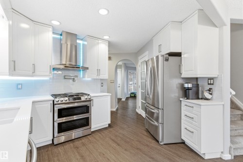 Modern kitchen featuring white cabinetry, stainless steel appliances, wood-finish flooring, recessed lighting, and a subway tile backsplash - 14755 131 Street Nw, Edmonton, AB - Indoor Photo Showing Kitchen