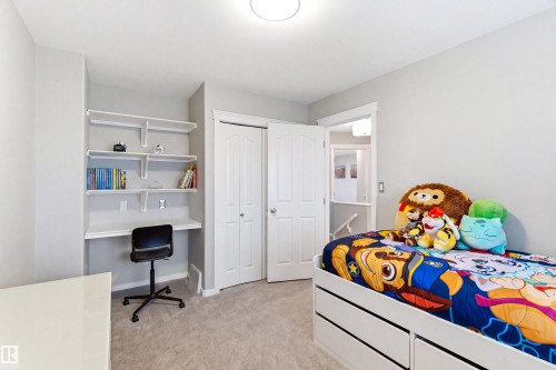 Built-in desk with integrated shelving, soft gray wall paint, light-colored carpeting, two panel doors, and a flush-mount ceiling light fixture - 14755 131 Street Nw, Edmonton, AB - Indoor Photo Showing Bedroom