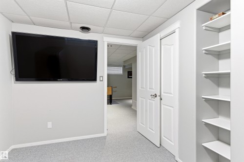 Recessed lighting illuminating built-in shelving, white paneled doors, and a suspended acoustic ceiling - 14755 131 Street Nw, Edmonton, AB - Indoor Photo Showing Other Room