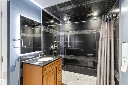 Contemporary bathroom featuring a dark tile shower with an integrated bench, mosaic accents, and overhead lighting - 14755 131 Street Nw, Edmonton, AB - Indoor