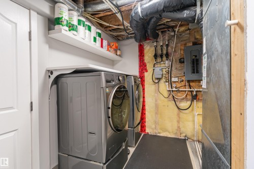 Laundry area featuring a floating shelf, white paneled door, exposed ceiling joists, and utility access - 14755 131 Street Nw, Edmonton, AB - Indoor Photo Showing Laundry Room