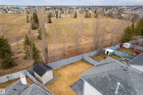Rear yard featuring a light-colored storage shed with a dark shingle roof, bordered by a wooden fence - 14755 131 Street Nw, Edmonton, AB - Outdoor With View