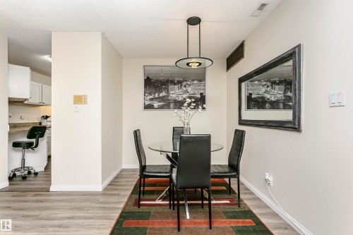 Dining area featuring wood-finish flooring and a contemporary pendant light fixture - 303 10026 112 Street, Edmonton, AB - Indoor Photo Showing Dining Room