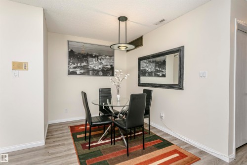 Dining area featuring wood-finish flooring, a modern ceiling light fixture, and light-toned wall paint - 303 10026 112 Street, Edmonton, AB - Indoor Photo Showing Dining Room