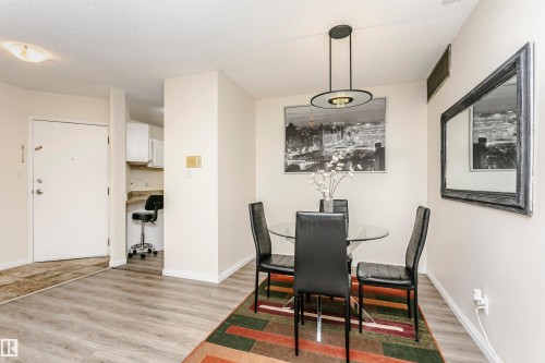 Spacious dining area featuring wood-finish flooring, a contemporary chandelier, light-toned walls, and white baseboards - 303 10026 112 Street, Edmonton, AB - Indoor Photo Showing Dining Room