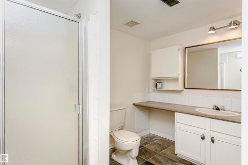 Bathroom featuring a frosted glass shower enclosure, a vanity with white cabinetry, an integrated sink, and a framed mirror - 303 10026 112 Street, Edmonton, AB - Indoor Photo Showing Bathroom