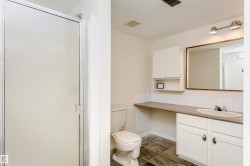 Bathroom featuring a frosted glass shower enclosure, a vanity with white cabinetry, an integrated sink, and a framed mirror - 
