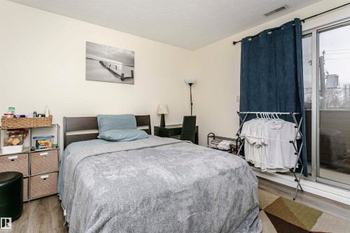 Spacious room featuring wood-finish flooring, a contemporary dark wood headboard, and light-toned walls - 303 10026 112 Street, Edmonton, AB - Indoor Photo Showing Bedroom