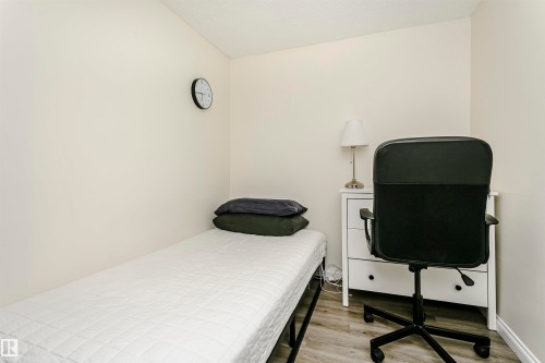 Neutral wall paint and wood-finish flooring highlight this space - 303 10026 112 Street, Edmonton, AB - Indoor Photo Showing Bedroom