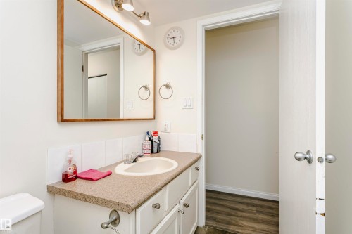 Bathroom vanity with a composite countertop, an undermount sink, and a framed mirror - 303 10026 112 Street, Edmonton, AB - Indoor Photo Showing Bathroom