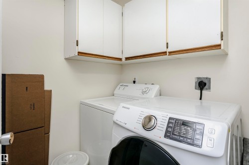 Dedicated laundry area featuring white upper cabinetry, light-toned walls, and utility hookups - 303 10026 112 Street, Edmonton, AB - Indoor Photo Showing Laundry Room