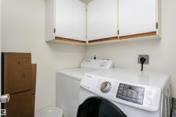 Dedicated laundry area featuring white upper cabinetry, light-toned walls, and utility hookups - 